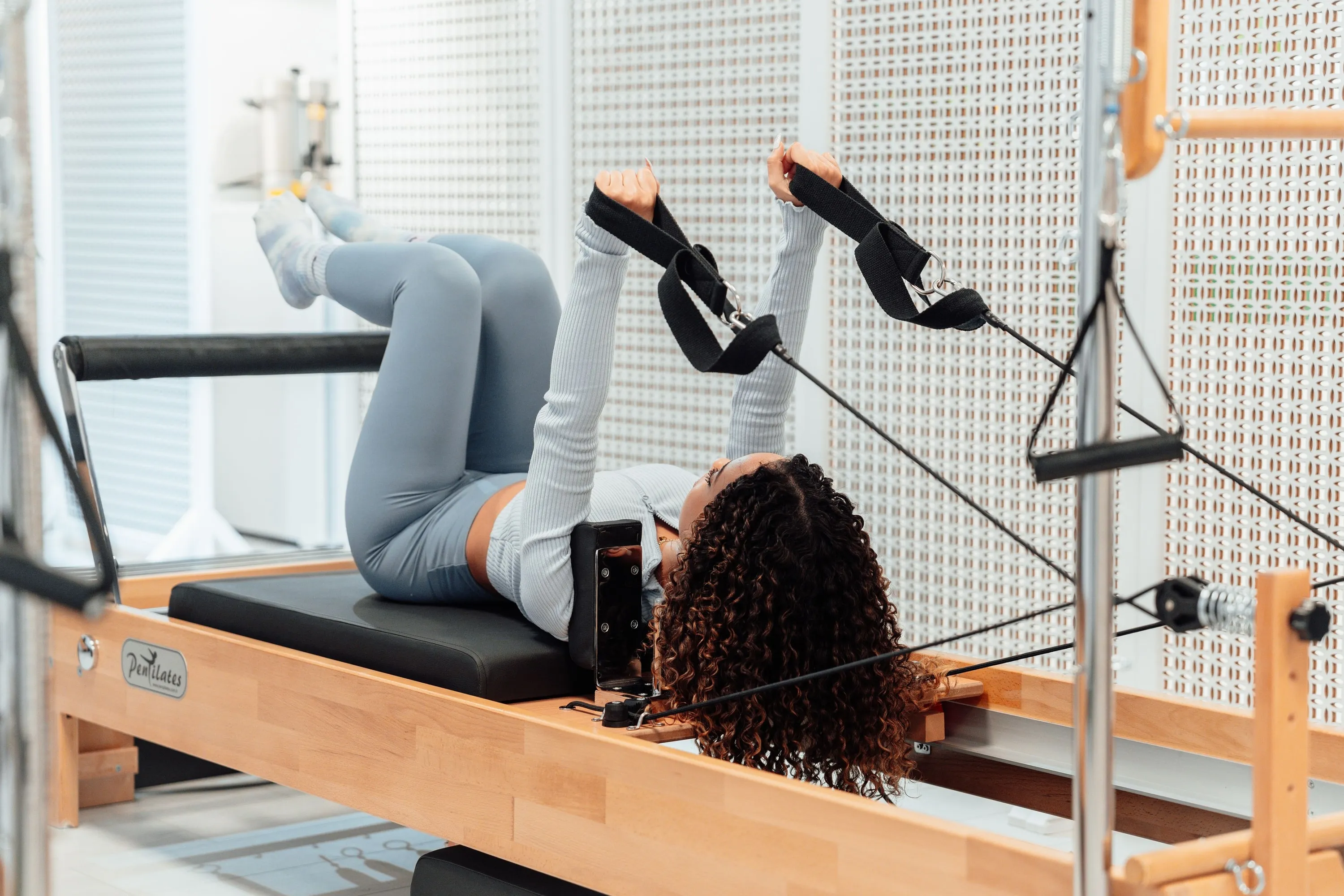 A close view of feet in the reformer straps, springs visible along the frame, mid-movement.
