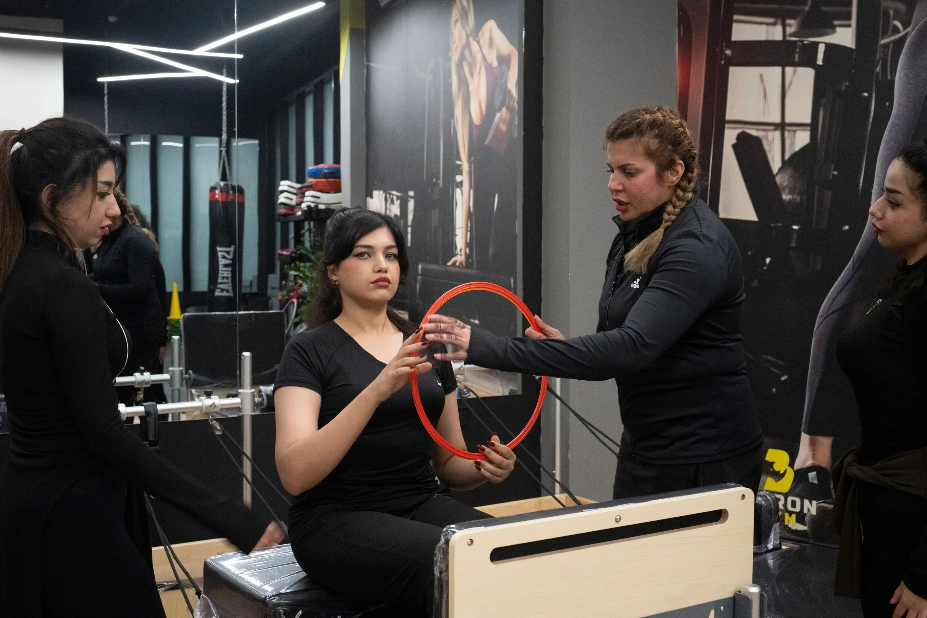 Elin passing a magic circle to a seated client mid-class, three others working around her.